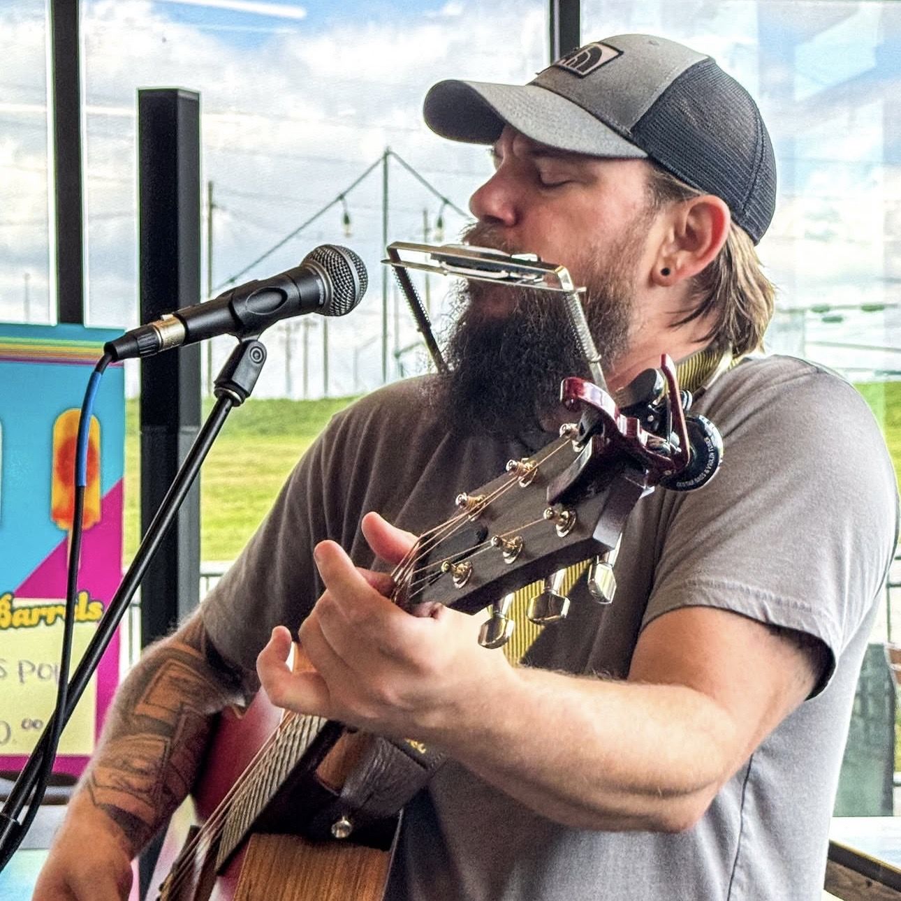 Colin Roberts playing guitar and harmonica at a brewery